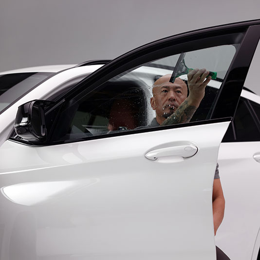 Installer placing window tint on a front window